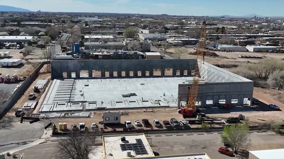 Aerial drone view of a commercial building under construction with a crane on site